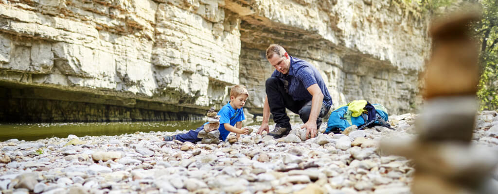 Vater mit Sohn spielt in Wutachschlucht mit Steinen